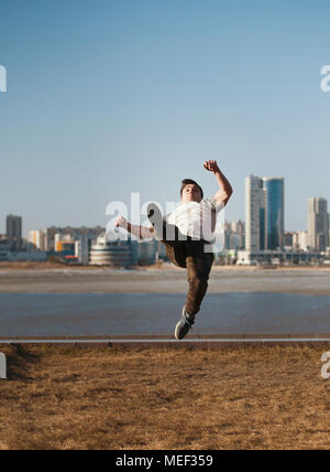 Jeune homme sportif parkour effectue des sauts acrobatiques devant skyline Banque D'Images