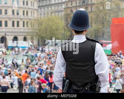Vue arrière d'un agent de police qui surveille les foules à Trafalgar Square, Londres Banque D'Images