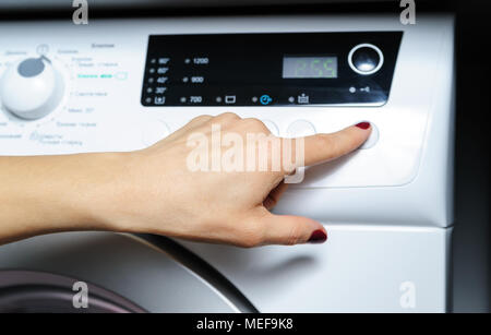 Faire tourner le lave-linge. Femme de doigt qui appuie sur le bouton de démarrage. Banque D'Images