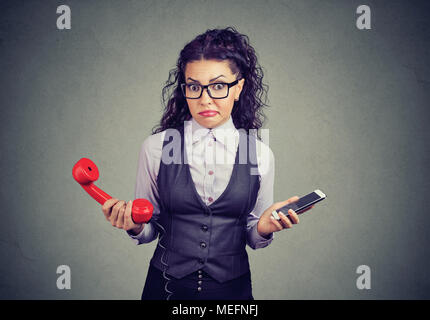 Femme officielle dans les verres holding old téléphone et nouveau smartphone à la perplexité face à l'appareil photo. Banque D'Images