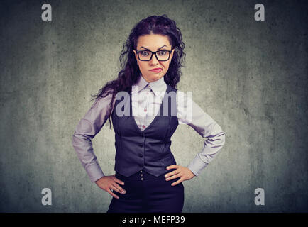 Femme en costume élégant et verres à la caméra en désaccord en tenant les mains sur les hanches. Banque D'Images