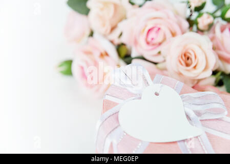 Boîte-cadeau avec étiquette, ruban et fleurs rose rose sur un fond clair Banque D'Images