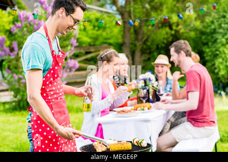 Man grilling meat sur jardin barbecue party Banque D'Images