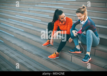 Deux jeunes femmes se reposant après le sport en plein air dans les escaliers Banque D'Images