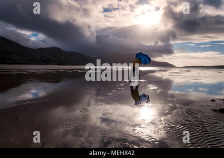 Ardara, comté de Donegal, Irlande la météo. 22 avril 2018. Un homme aux prises avec un parapluie tout en prenant une promenade sur la plage par un jour de vent avec beaucoup d'averses de pluie sur la côte ouest. Crédit : Richard Wayman/Alamy Live News Banque D'Images