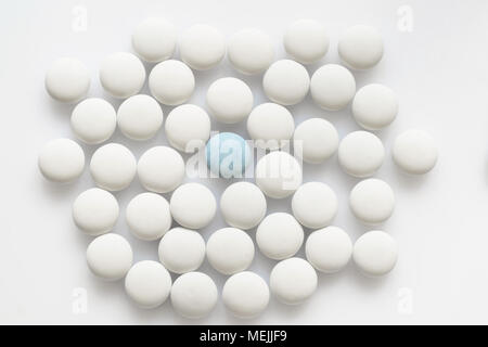 L'un bleu et beaucoup pilules blanches sur une surface d'éclairage Banque D'Images