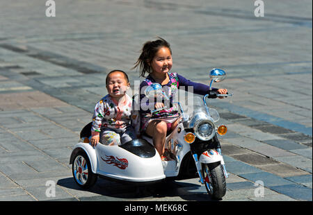 6 à 8 ans, un cheval jouet électrique motor-bike avec son frère sur Sukhbaatar Square, Ulaanbaatar, Mongolie Banque D'Images