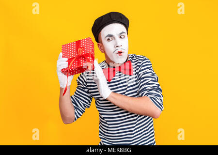 Ce qui est à l'intérieur de fort ? Mime perplexe man holding red box Banque D'Images