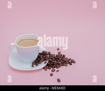Grains de café torréfié dispersés dans une tasse sur un fond rose, copiez l'espace. Banque D'Images