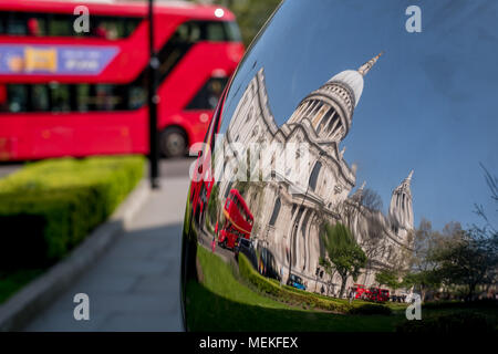 Reflet déformé de la Cathédrale St Paul, London UK, reflétée dans la surface en métal brillant miroir de sculpture, blurred bus rouge à l'arrière-plan. Banque D'Images