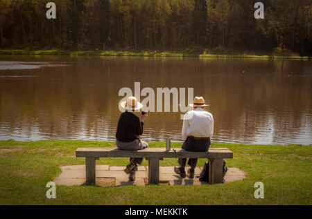 Vieux couple assis sur un banc en face du lac bénéficiant d'une fiole de thé ou café dans sunshine Banque D'Images