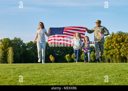 Soldat et sa famille sont marche La marche des drapeaux américains. Banque D'Images