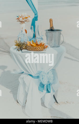 Décoration de table avec bouteille de champagne, refroidisseur, verres et fruits. Les préparatifs de mariage à la plage tropicale. Banque D'Images