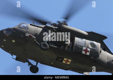 Un chef d'équipe de l'armée américaine avec le soutien général st 2-501Aviation Battalion (GSAB), 1re Division blindée, basé à Ft. Bliss, Texas, peeks légèrement hors d'un HH-60M, l'évacuation médicale en s'assurant qu'il est en sécurité à la terre ci-dessous lors de l'intervention d'un tuteur 18 à Muscatatuck Urban Training Centre, Ind., 20 avril 2018. Plus de 4 500 soldats de partout au pays participent à l'intervention d'un tuteur 18, un exercice d'entraînement multi-composants pour valider la capacité des unités de l'armée américaine pour soutenir l'appui de la défense aux autorités civiles (DSCA) dans le cas d'un produit chimique, biologique, radiologique et nucléaire (CBRN) cat Banque D'Images