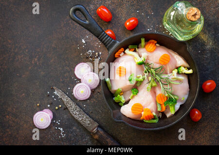 La viande fraîche. Filet de poulet crus sur un poêle en fonte, d'épices et de légumes frais sur une table de cuisine. Banque D'Images