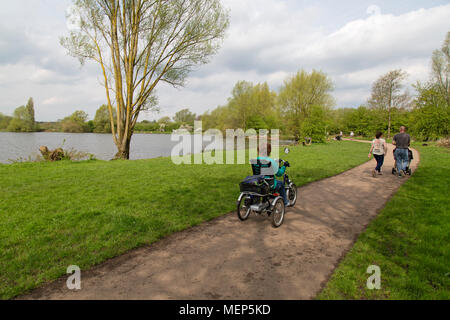 Shave Farm Country Park dans le Leicestershire, Angleterre. Une femme dans un cycle spécialement adaptés, et une jeune famille, sur un chemin autour d'un lac. Banque D'Images