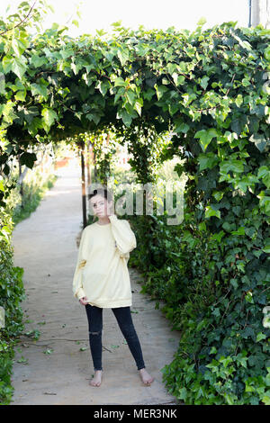 Portrait d'une jeune adolescente dans un jardin. Tir vertical avec lumière naturelle. Banque D'Images