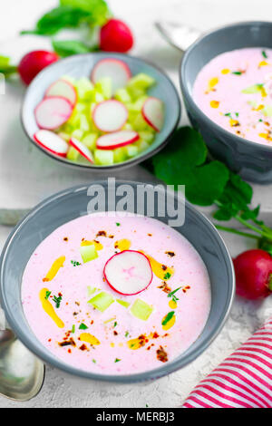 Soupe de radis froide rose avec le concombre et yaourt garnie de piment sec, le poivre, le persil, l'huile d'olive et servi dans des bols crudités Banque D'Images