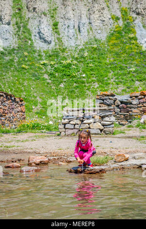 KETRISI, GÉORGIE - 17 juillet : Local girl in pink laver ses mains dans la rivière, dans la vallée de Truso. Juillet 2017 Banque D'Images