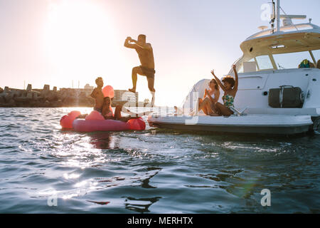 Jeune homme de plonger dans la mer de yacht avec acclamations d'amis. Groupe d'amis ayant un grand vacances d'été.