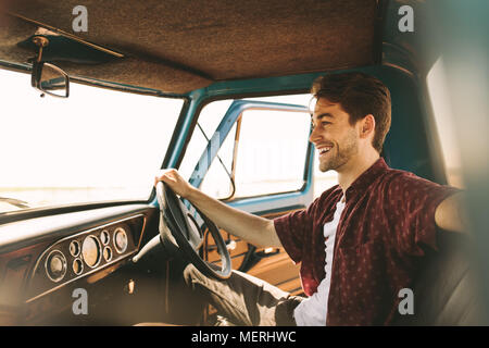 Couple assis sur le siège d'une vieille voiture. Homme assis dans son vintage car maintenant la roue avec la porte ouverte. Banque D'Images