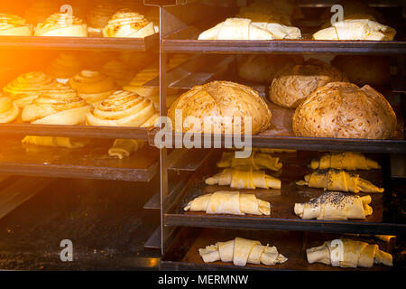 Un gros plan de la pâtisserie pains ronds de fromage, pain, croissants avant la cuisson dans des lignes droites sur le fer à repasser plaques de cuisson dans une boulangerie Banque D'Images