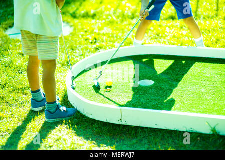Es enfants jouer sur le terrain de golf.Les enfants occasionnels à un terrain de golf tenue de golf. Coucher du soleil Banque D'Images