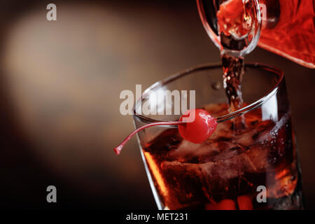 Whiskey est versé d'une carafe en verre avec de la glace.Manhattan Cocktail avec cerise.Copier l'espace. Banque D'Images