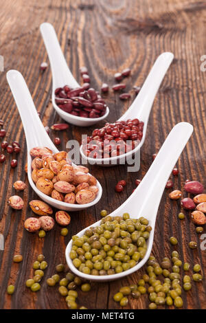 Divers Les haricots frais dans les cuillères sur table en bois. Saine alimentation végétarienne et végétalienne. Banque D'Images