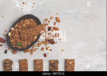 Les barres granola et les ingrédients. Dessert sucré saine collation. Barre granola vegan aux noix, chocolat et fruits rouges sur un fond blanc. Vue de dessus, copiez s Banque D'Images