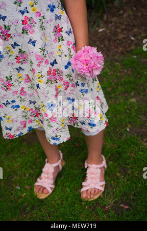 Fille robe à fleurs en tenant un petit bouquet de fleurs roses Banque D'Images