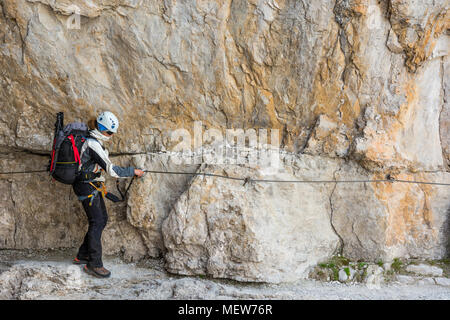 Climber marche sur corniche étroite protégés par via ferrata fixé. Banque D'Images