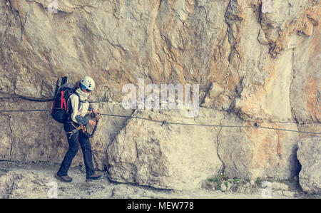 Climber marche sur corniche étroite protégés par via ferrata fixé. Banque D'Images