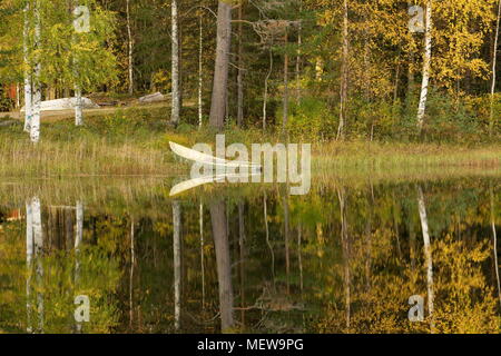 Un bateau à rames en attente se trouve au bord d'une forêt paisible lac en automne Banque D'Images
