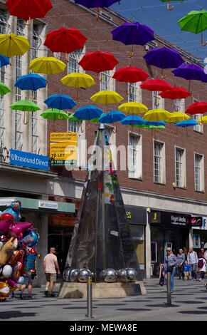 Vendeur de ballons sur High Street, Exeter Exeter avec la sculpture et l'Obélisque Riddle printemps coloré de parasols. Devon, Royaume-Uni. Avril, 2018. Banque D'Images