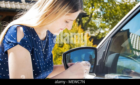 Belle jeune femme lave-miroirs latéraux de sa voiture Banque D'Images