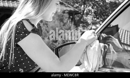 Noir et blanc photo de jeune femme le polissage et d'essuyage des vitres de voiture Banque D'Images