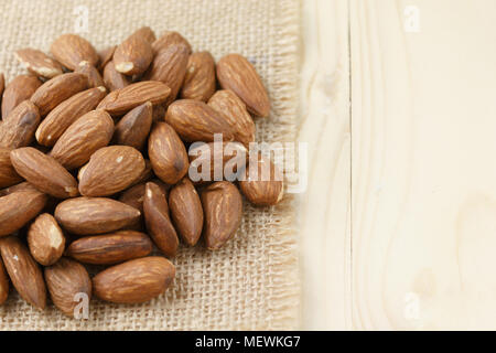 Amandes rôties sur un sac placé sur une table en bois, les amandes background Banque D'Images