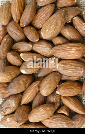 Amandes rôties sur un sac placé sur une table en bois utiliser pour le fond Banque D'Images