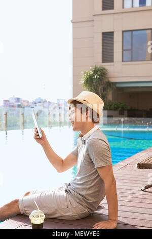 Handsome asian man relaxing by extérieure et lecture d'e-book Banque D'Images