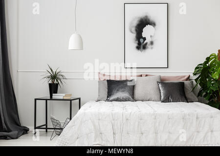 Hôtel lumineux intérieur chambre à coucher avec des plantes en pot, des livres sur la table en métal et d'affiches sur le mur Banque D'Images