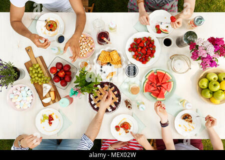Groupe multiculturel d'aliments sains comme les fruits de partage et de fromage à l'extérieur avec des fleurs sur la table Banque D'Images