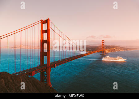 Belle vue panoramique de navire de croisière passant célèbre Golden Gate Bridge avec la skyline de San Francisco en arrière-plan au coucher du soleil, en Californie Banque D'Images