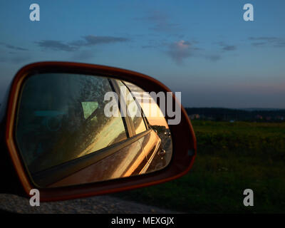 Young man photographing coucher de soleil depuis la voiture à plein régime avec son appareil photo vintage Banque D'Images