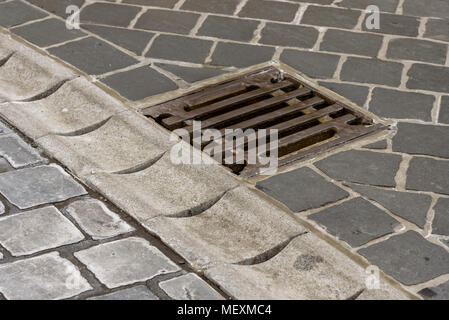 Un réservoir pour recueillir l'eau après une pluie et une grille d'égout le long de la route Banque D'Images