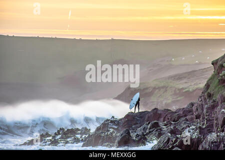 Personne tenant debout sur voile de Pembrokeshire Coast rocheuses pendant le coucher du soleil.L'humain et la nature, la solitude.Surfer sur le bord de mer.uk zone côtière. Banque D'Images