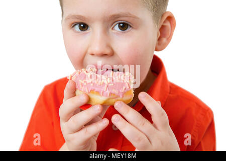 Peu de professionnels cute boy eating donut est sur fond blanc mur. enfant s'amuse avec anneau. La nourriture bonne pour les enfants. Drôle de temps à la maison avec un aliment sucré. Kid lumineux. Banque D'Images