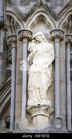 Sculpté patiné statue en pierre de St Jean l'évangéliste à l'extérieur du mur ouest de la cathédrale médiévale de Salisbury, Angleterre. Banque D'Images