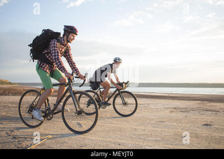 Deux jeunes hommes sur un vélos de cyclotourisme avec des sacs et casques dans le désert sur un voyage en vélo, amis'avoir in sunny day Banque D'Images