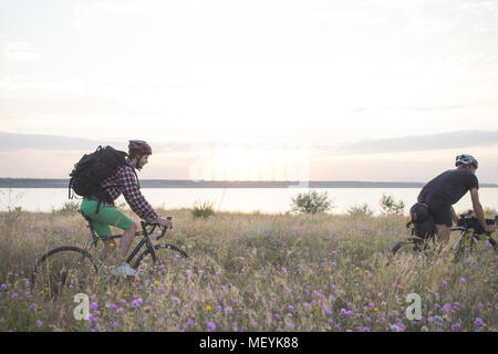 Deux jeunes hommes sur un vélos de cyclotourisme avec des sacs et casques dans le désert sur un voyage en vélo, amis'avoir in sunny day Banque D'Images
